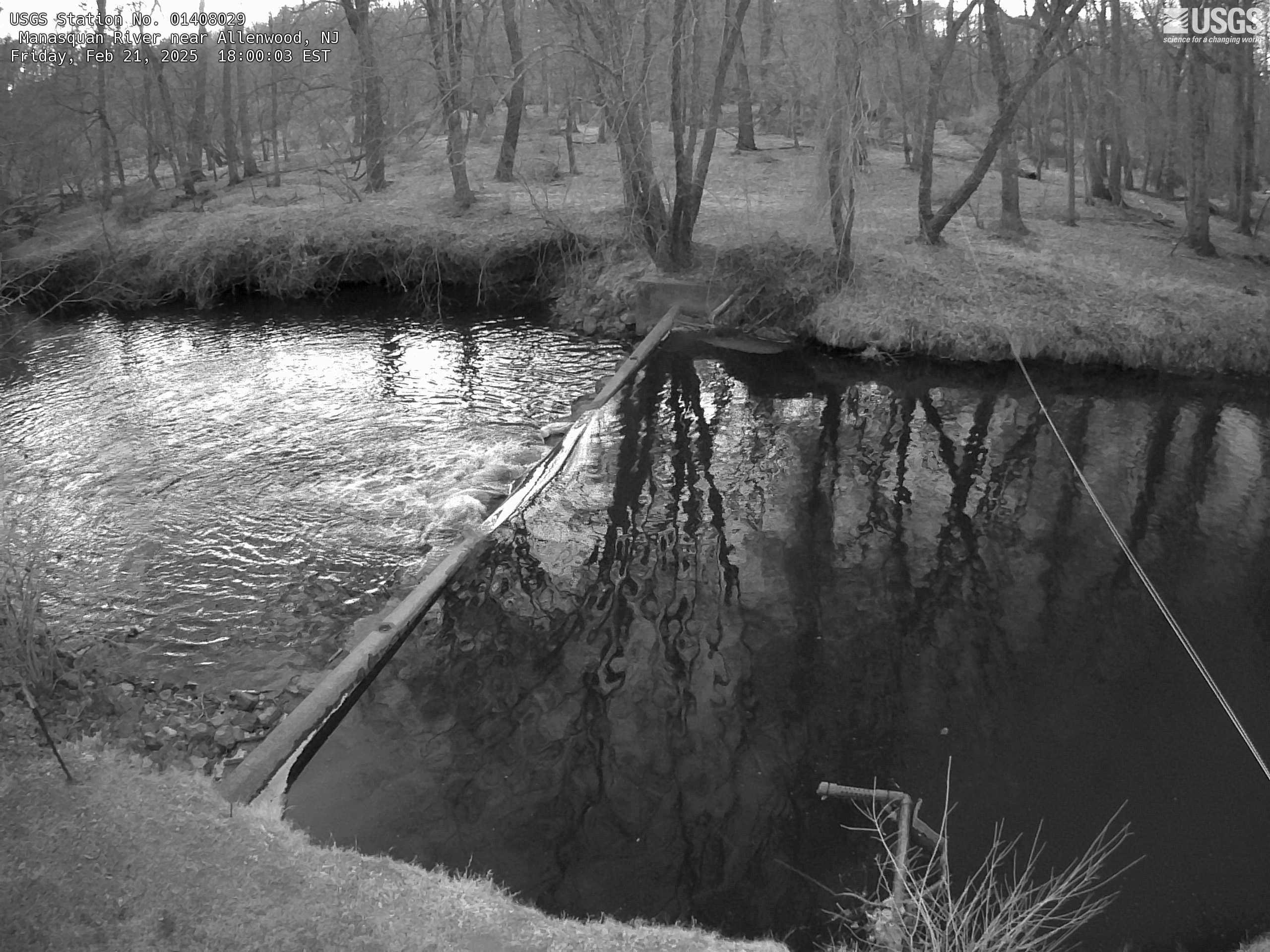 Looking down upon the river flowing over a weir far below the gage