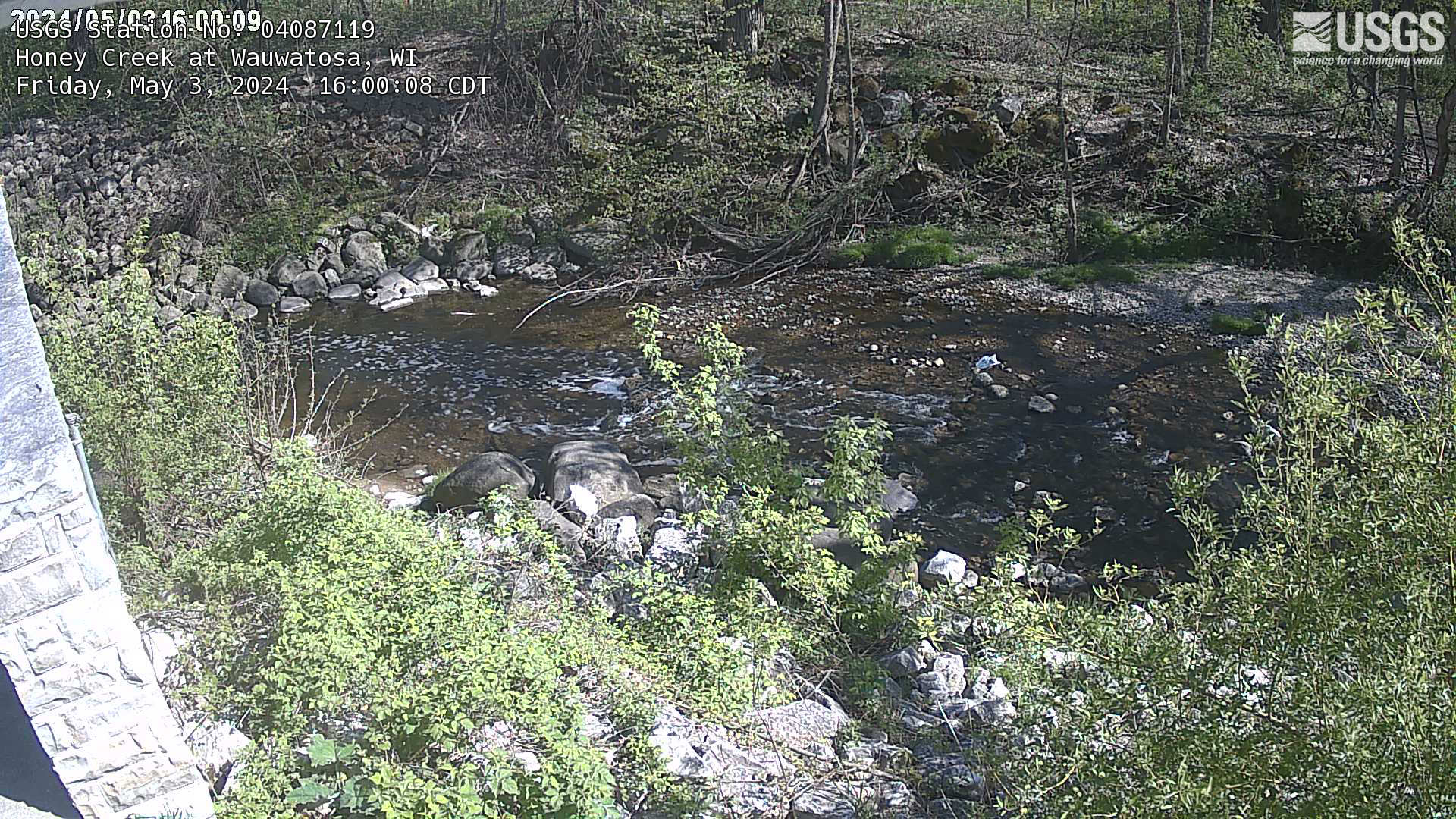 Overlooking a creek with rock and brush on both sides.