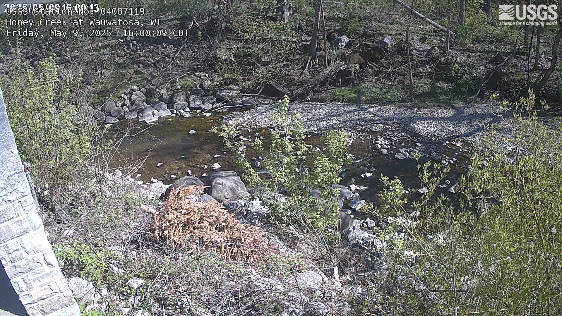 Overlooking a creek with rock and brush on both sides.